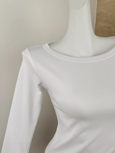 Close-up of white ribbed knit fabric texture on a slim-fit long-sleeve top