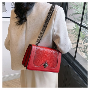 Detail of red snake pattern leather crossbody bag with geometric lock on model back