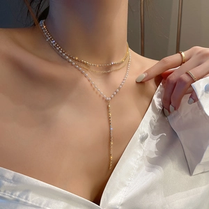 Detail view of multi-layer gold layered necklaces with white pearls and metal tassels