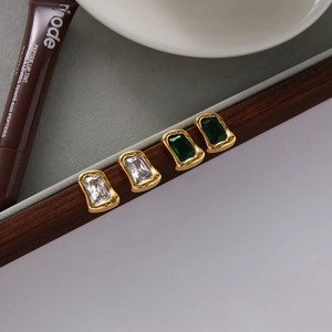 Detail van rechthoekige groene en heldere zirkoon oorbellen in vintage gouden zettingen