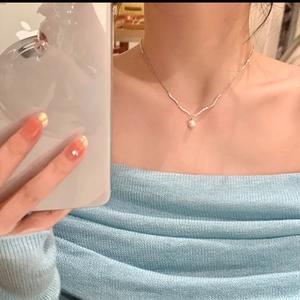 On-model view of silver V-shaped necklace with zircon stones and a round pearl pendant