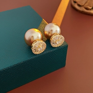 Detailed shot of gold plated pearl earrings with zircon inlay on luxury green box