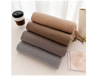 Close-up of neatly folded soft wool scarves in beige, brown, and grey neutral tones