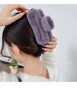 Large purple plush hair claw clip worn on model's hair showing secure fit and soft texture