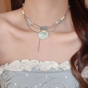 Detail of layered ocean necklace with pearls, blue stones, and green shell pendant