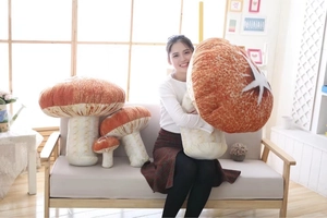 Detail showing various sizes of realistic red mushroom plush pillows in a cozy home setting