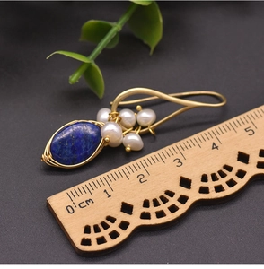 Detail of lapis lazuli and freshwater pearl drop earrings with gold wire wrap and ruler