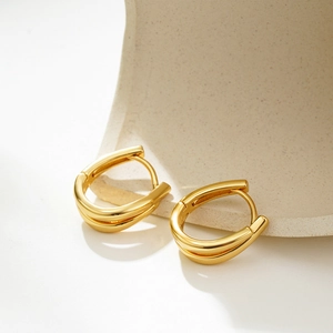 Detail of polished 18K gold U-shaped earrings featuring a modern geometric double-line design