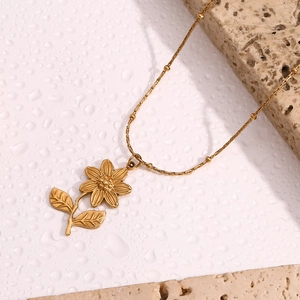 Détail du pendentif fleur de lotus plaqué or 18K sur une chaîne à perles avec pierre