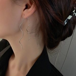 Close-up of elegant silver wave tassel threader earrings worn by a model