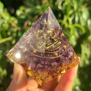Close-up of Orgone pyramid with amethyst stones, gold foil, and metal Buddha statue