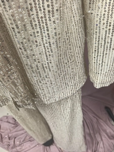Detailed close-up of shiny sequin fabric texture on luxury high-waist suit trousers