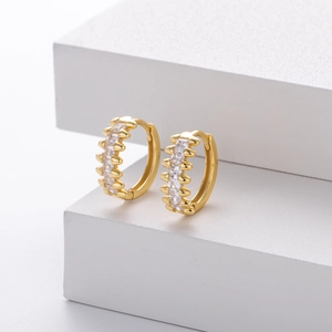 Close-up of gold hoop earrings with micro-pave rectangular cubic zirconia on white steps
