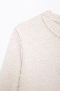 Close-up of cream white knit sweater showing fuzzy texture and ribbed round neckline