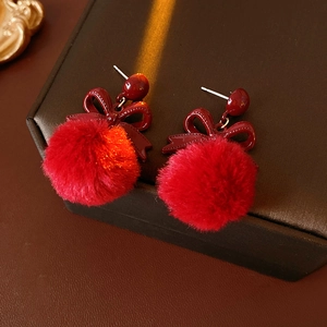Detail of red plush ball earrings with bow decoration on premium leather jewelry box