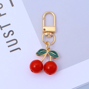 Detailed view of sweet red cherry keychain with gold hook and green enamel leaves