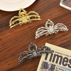 Detailed view of alloy spider hair claws in gold, silver, and black on a wooden background