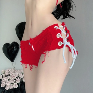 Dettaglio macro degli hot pants in denim rosso con lacci laterali e design sexy ritagliato