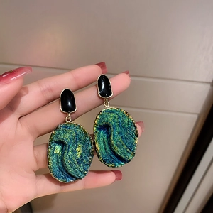 Detail of teal resin earrings with gold edges and vintage textured drop style