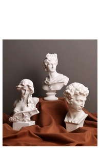 Macro shot of three matte white classical bust statues used as artistic metal ashtrays