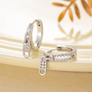 Unique silver zipper pendant hoop earrings with zircon stones on a warm aesthetic background