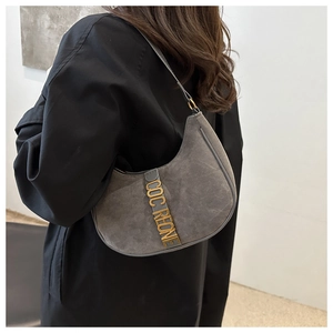 Detail showing the gray suede crescent shoulder bag texture and metal letter logo