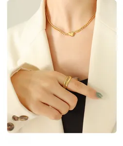 Detail of model wearing a gold heart pendant necklace and a braided texture band ring