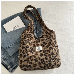 Detail shot of leopard print faux fur shoulder bag with woven label on a textured background