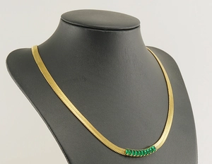 Detail of 18K gold-plated snake chain necklace with rectangular green zircon accents