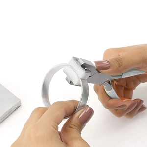 Manual bracelet bending pliers with white nylon jaws shaping a silver metal ring blank