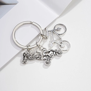 Close-up of a silver metal keychain featuring detailed bicycle and motorcycle charms