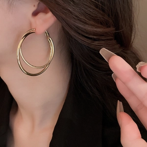 Gros plan de boucles d'oreilles géométriques dorées portées par un mannequin en studio