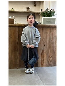 Detail of denim mini crossbody bag with gold chain strap on a child's shoulder