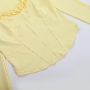 Detailed macro shot of light yellow top featuring boning structure and ruffle trim edges
