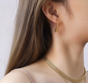 Close-up of golden liquid drop earrings and a wide woven mesh choker necklace