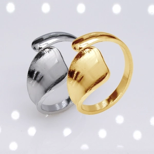 Polished gold and silver adjustable stainless steel rings on a reflective studio surface