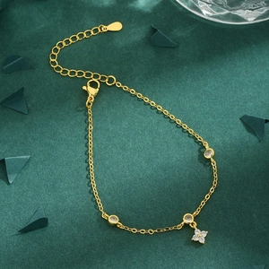 Elegant gold clover bracelet with circular zircon charms and lobster clasp on dark background