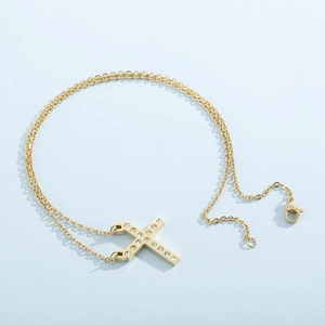 Detail of a golden cross necklace with crystal pavé and elegant double layered chain