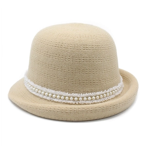 Close-up of beige knit cloche hat with white lace trim and pearl bead decorations