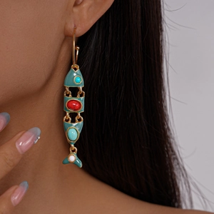 Close-up of articulating fish drop earrings with colorful enamel and gold finish