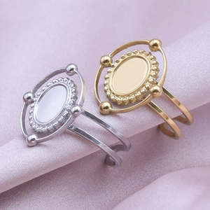 Macro detail of geometric oval ring bases in silver and gold on soft silk fabric