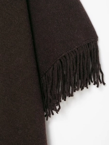 Close-up of deep brown knitted fabric texture with elegant tassel fringe details