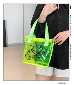 Detail of neon green transparent PVC tote bag with stylish black butterfly patterns