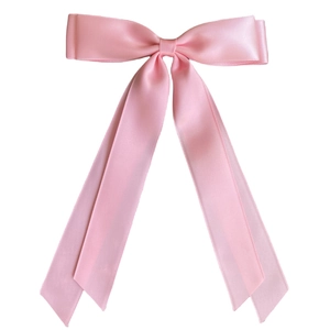 Close-up of a pink satin ribbon hair clip with long flowing tails on white background