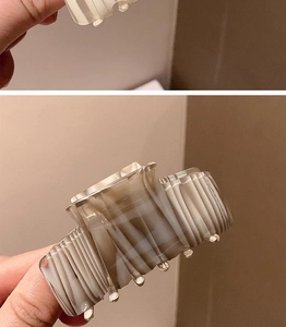 Detail of gray and white ink-pattern acetate hair claw clip with multi-tooth structure