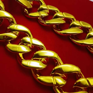 Macro shot of gold-plated thick Cuban link chain necklace on a red background