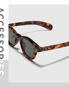 Detail of round tortoiseshell sunglasses with green lenses and metal star rivets