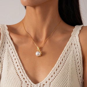 Detail of vintage gold necklace featuring a round white pearl pendant with zircon accents