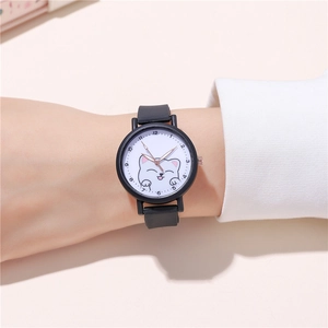 Detailed view of a black cartoon cat watch with white dial on a wrist over a sweater