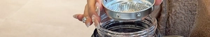 Close-up of a stainless steel tea infuser being placed into a borosilicate glass cup
